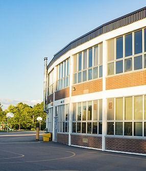 School building with large windows, brick and white facade, sunny day.