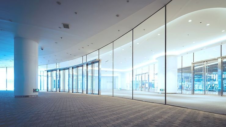 A large commercial empty office with a lot of windows and a carpeted floor.