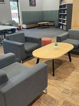 Cozy library area with gray armchairs, a light wood coffee table, and a built-in bench with green backing.