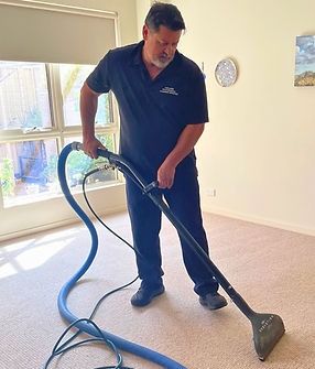 A man is using a vacuum cleaner to clean a carpet in a living room.