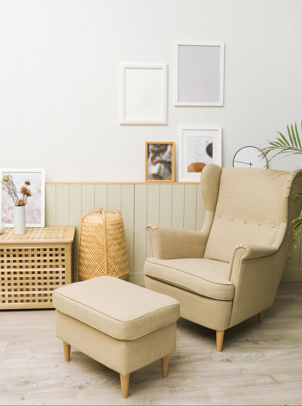 Beige armchair with ottoman in a light-colored room, with framed art and a wicker basket.