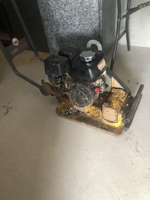 A Yellow and Black Plate Compactor With a Gas Engine on a Concrete Floor — Cairns Small Engine Repairs in Bentley Park, QLD