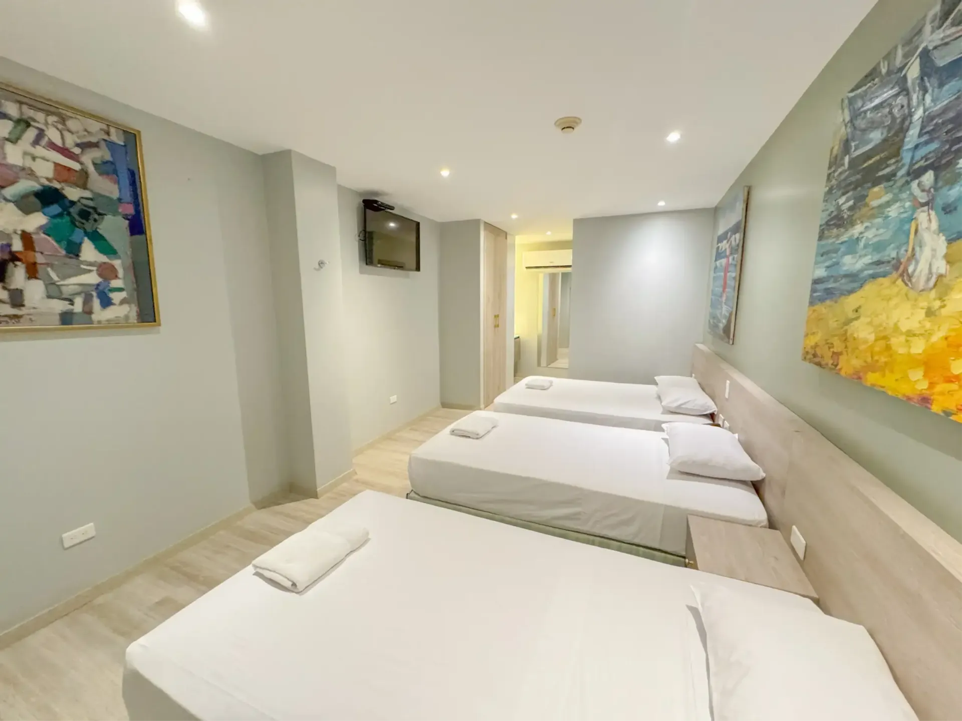 Un dormitorio con tres camas y una pintura en la pared