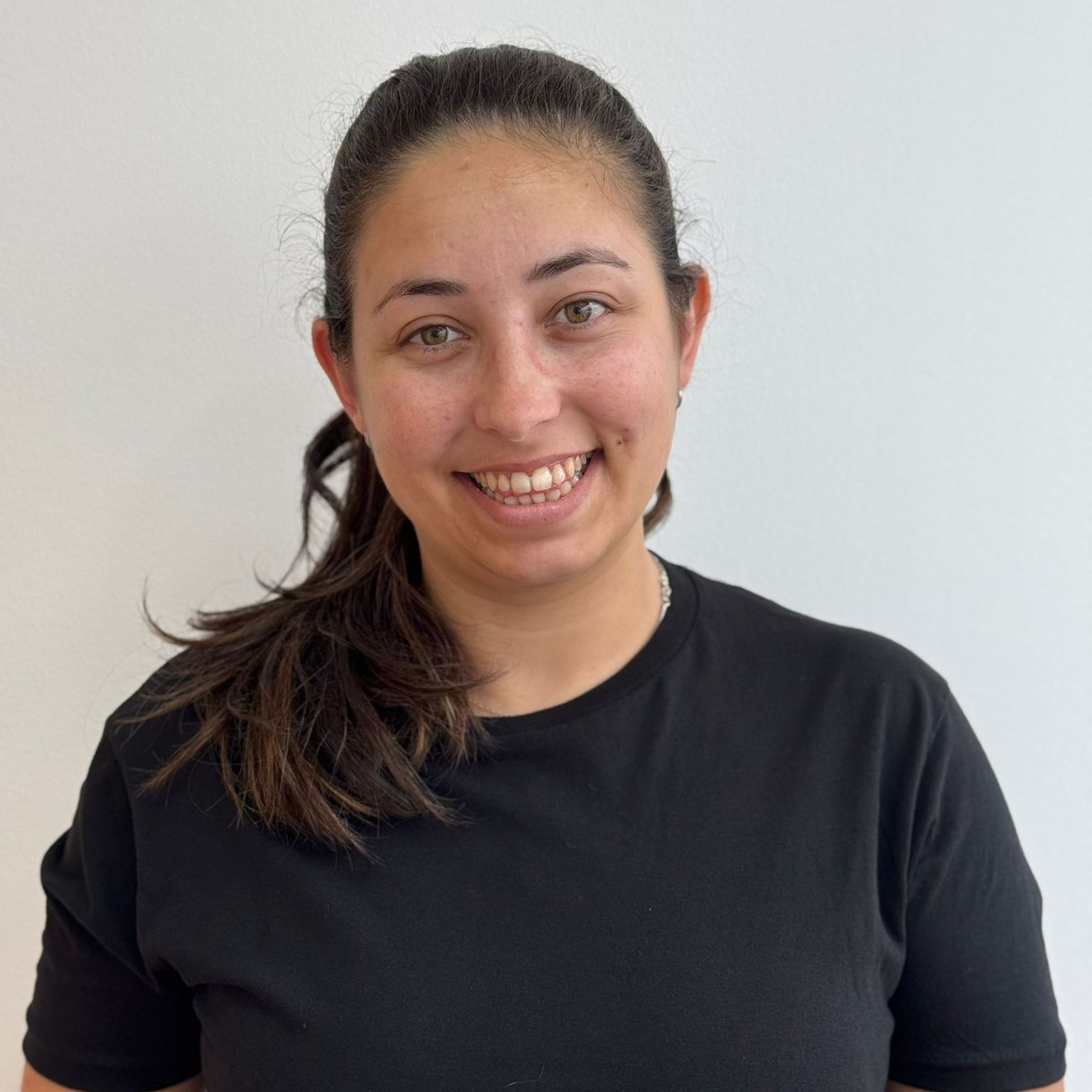 Woman with brown hair in a black shirt smiles. Set against a white background.
