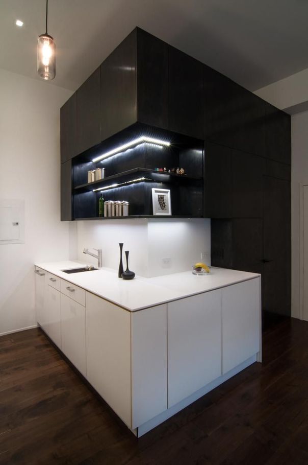 A kitchen with white cabinets and a black wall