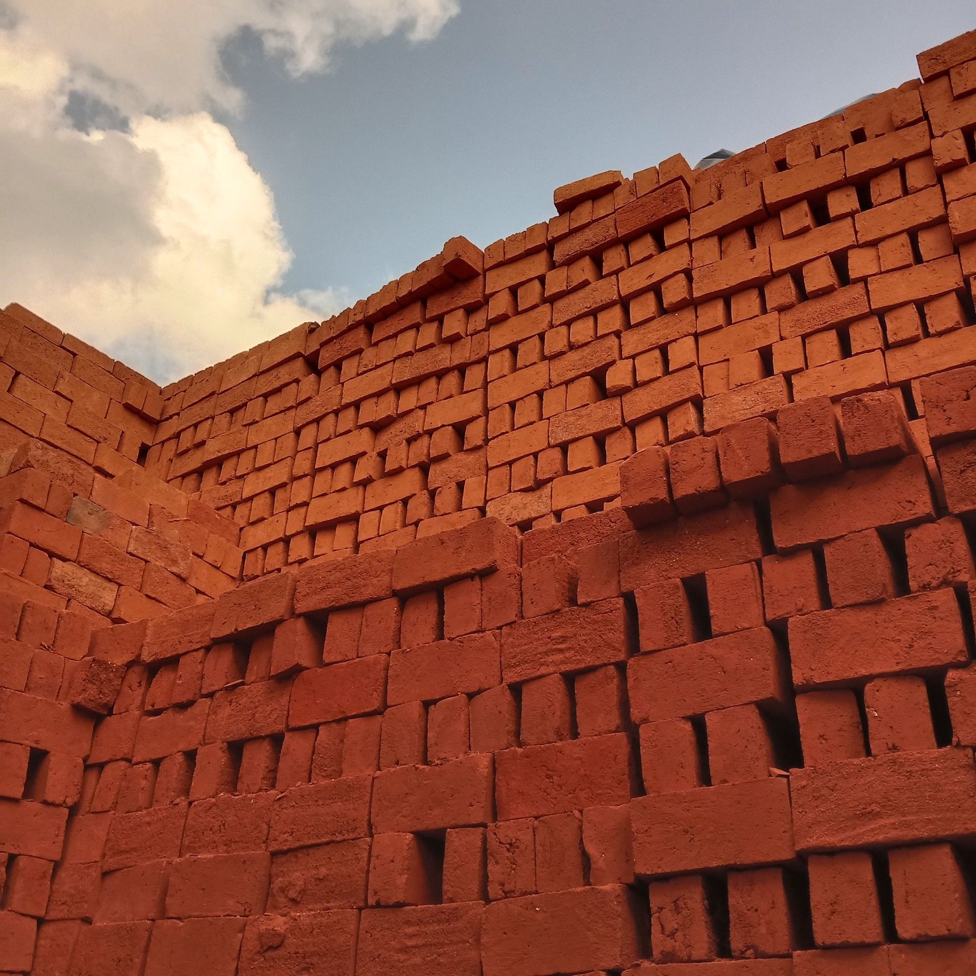 A stack of red bricks against a cloudy sky