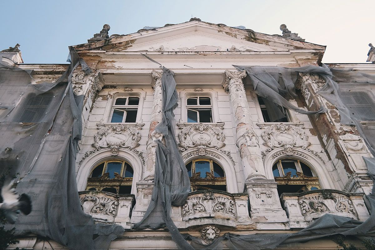 A large building with a lot of windows is covered in a tarp.