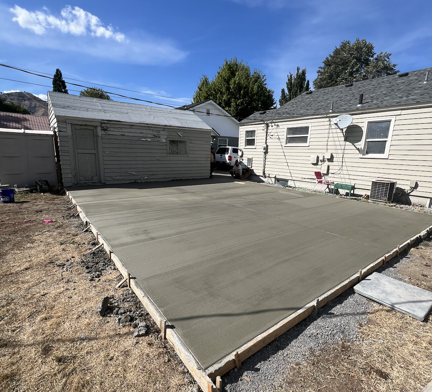 A concrete driveway is being built in front of a house.