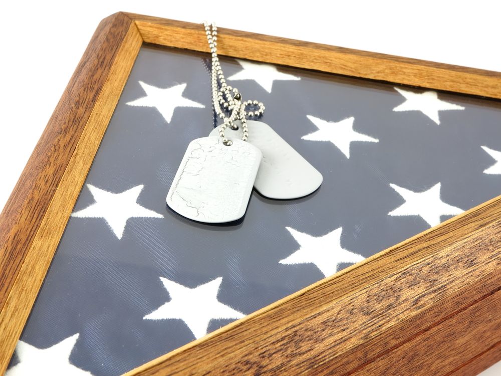 Dog tags and necklace on a star-patterned photo frame with a wooden border