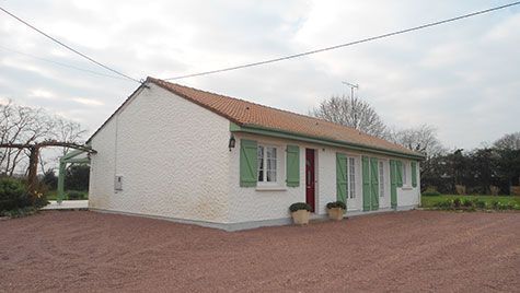 Une maison blanche avec des volets verts et une porte rouge