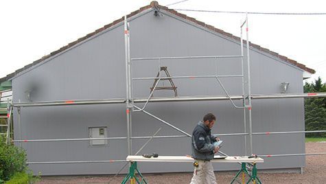 Un homme se tient devant un bâtiment avec un échafaudage.