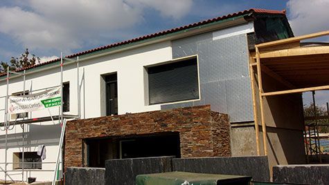 Une maison est en construction avec des échafaudages autour.
