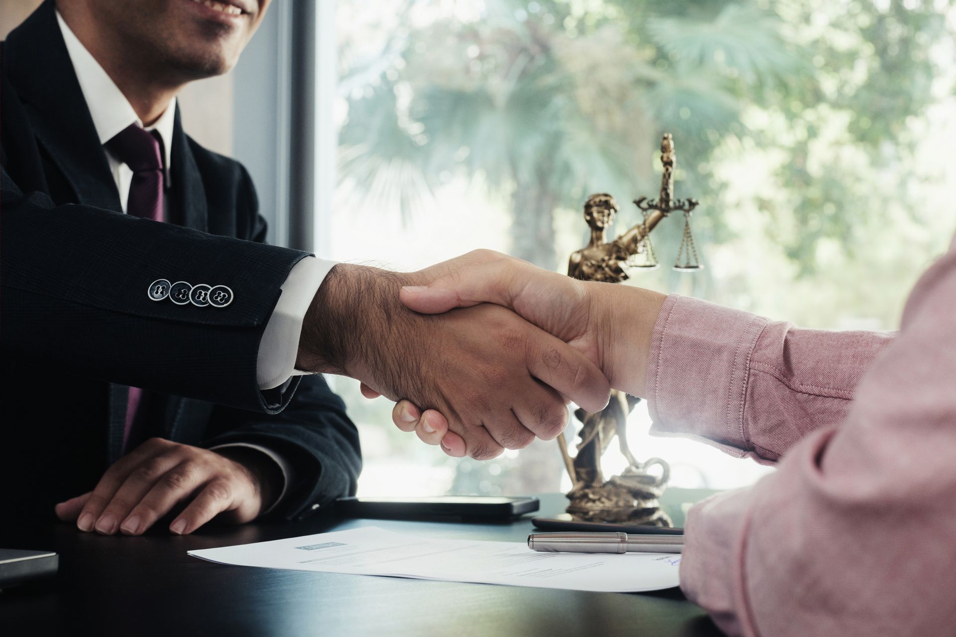 Two people shaking hands, a symbol of justice in the background.