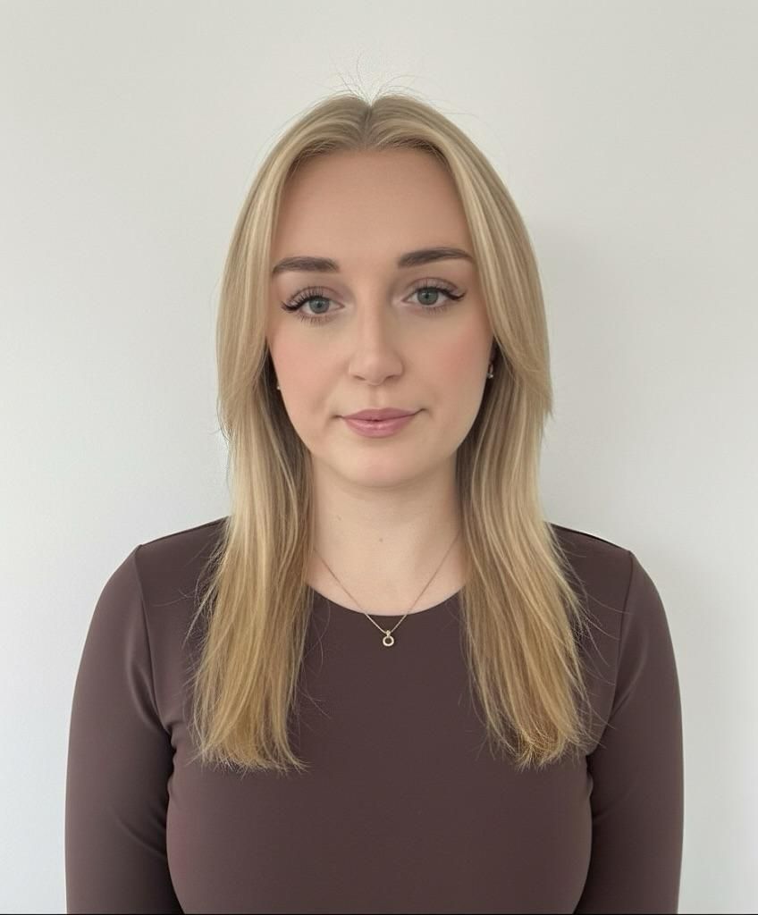 Blonde woman in a brown long-sleeved shirt, looking directly at the camera against a white background.