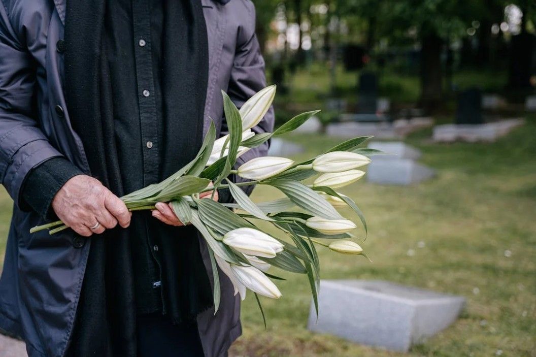Person holding white lilies at a cemetery for caring funeral and cremation support near Kingston, WA