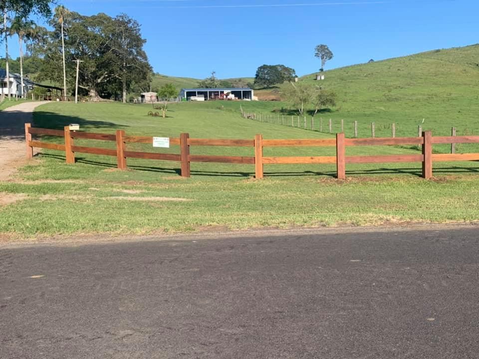 A Grassy Field Is Bordered By A Wooden Fence — Lawrence Williams Fencing in Goolmangar, NSW