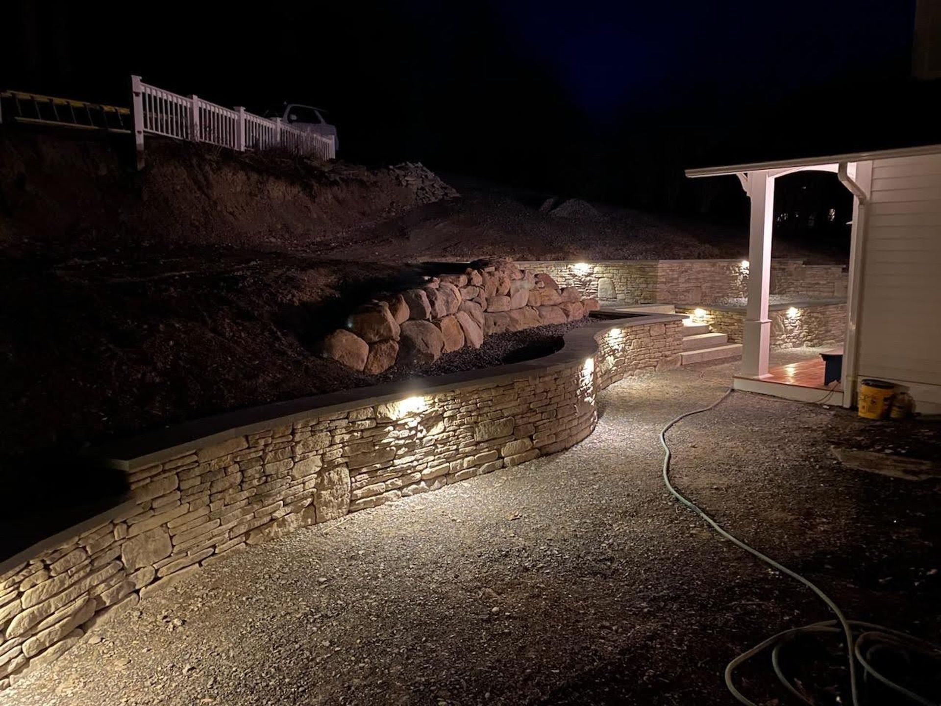 A stone wall is lit up at night in front of a house