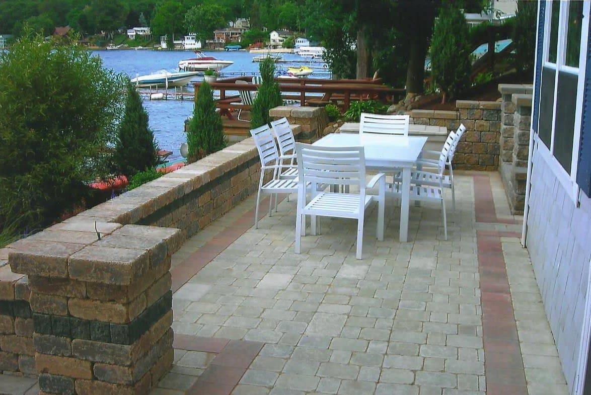 A patio with a table and chairs overlooking a lake