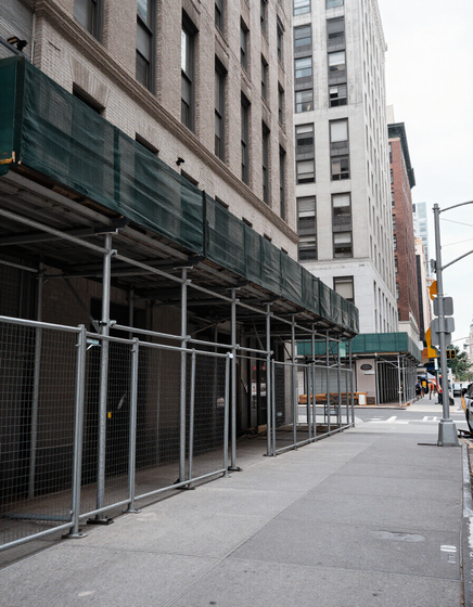 NYC building exterior with scaffolding and construction fence