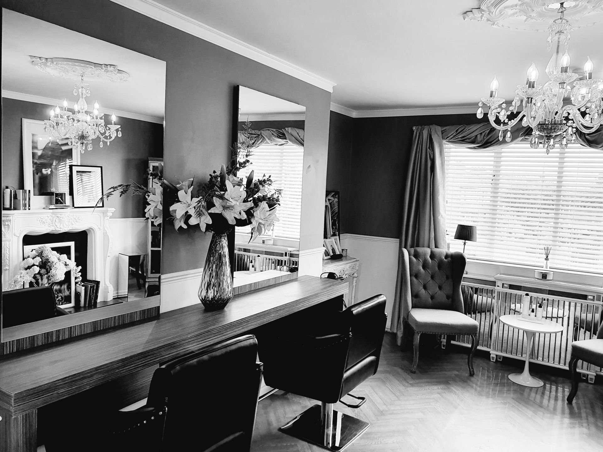 A black and white photo of a hair salon with chairs and mirrors.