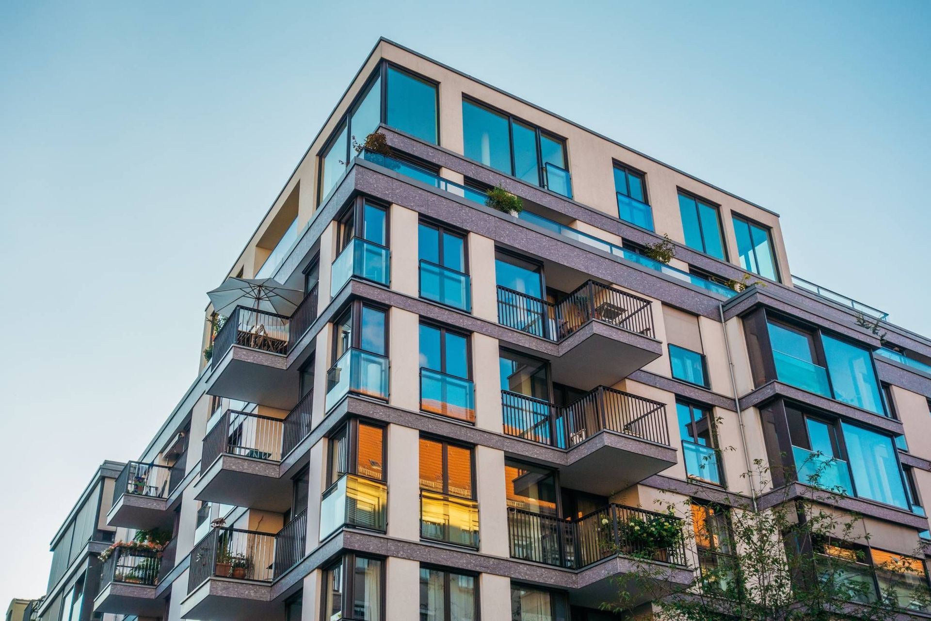 Modern apartment building with balconies, gray and white facade, blue sky.