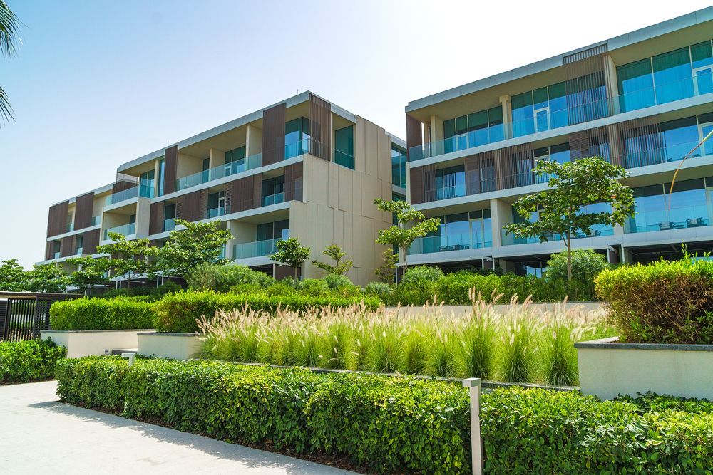 Modern apartment building with balconies, lush landscaping, and blue sky.
