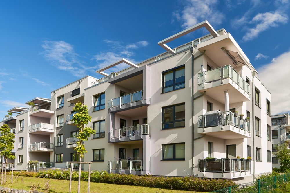 A large apartment building with balconies and a blue sky in the background.