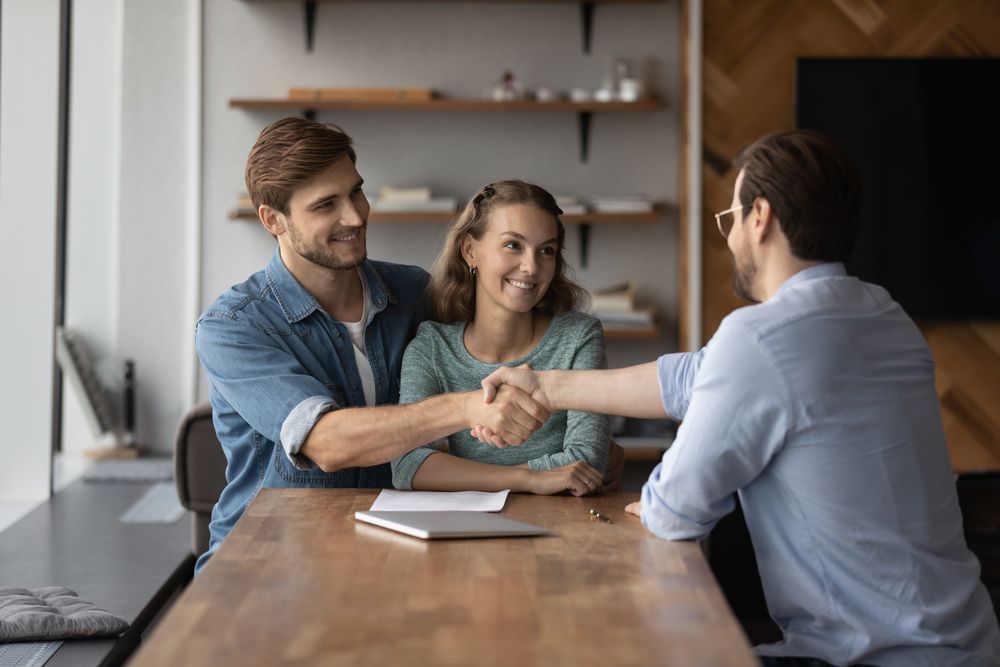 A man and a woman are shaking hands while sitting at a table.