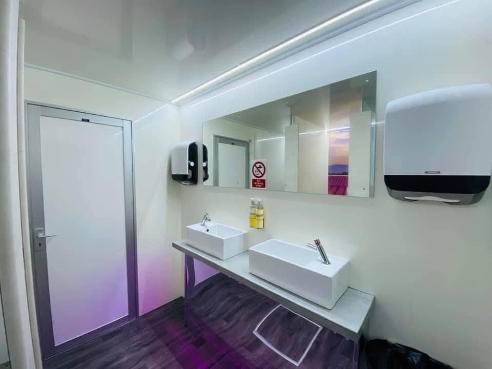 Interior of a public restroom with two sinks, a large mirror, and paper towel and soap dispensers.