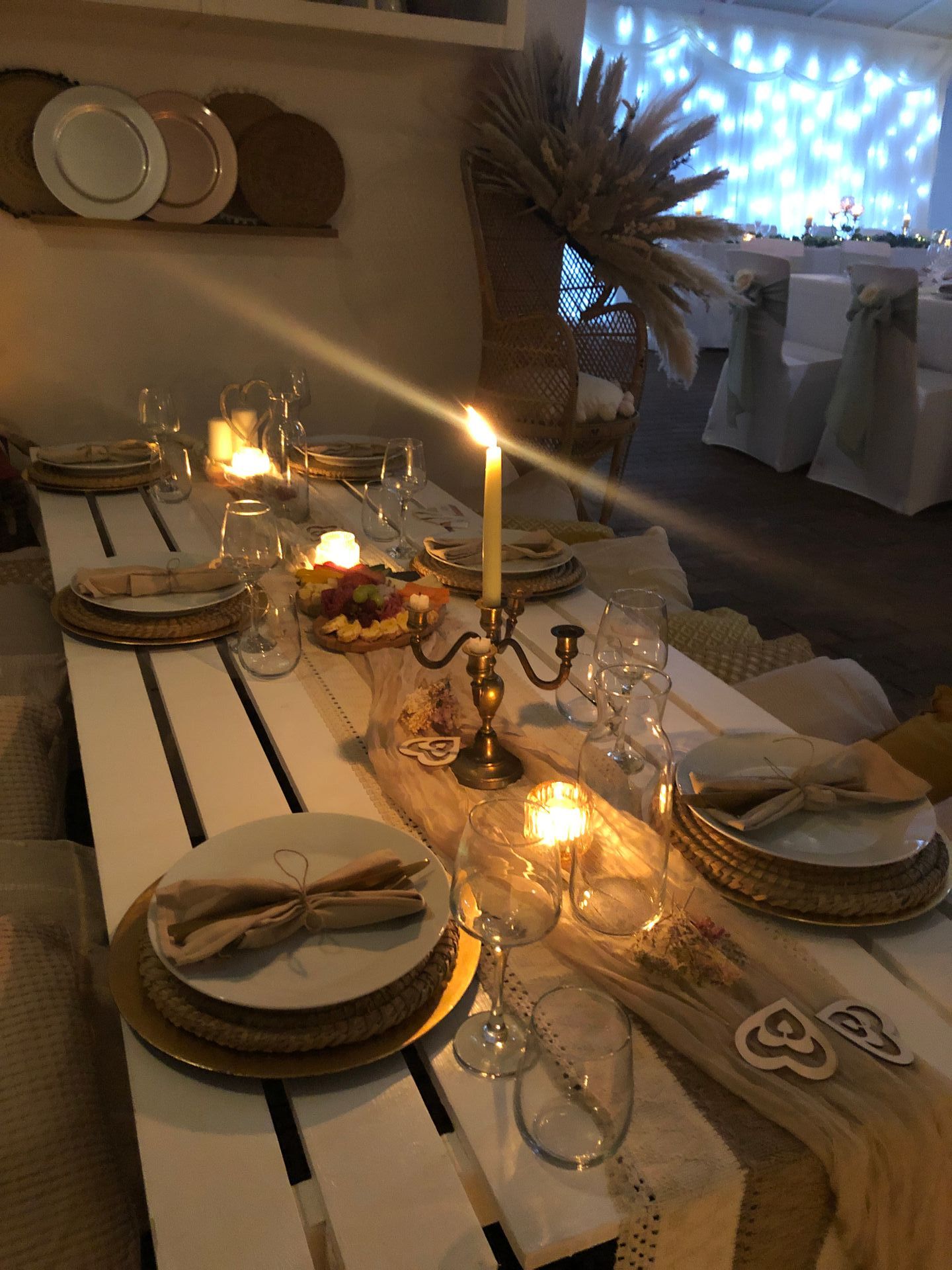 Elegant table setting with gold chargers, candles, and a floral centerpiece in a warmly lit room.