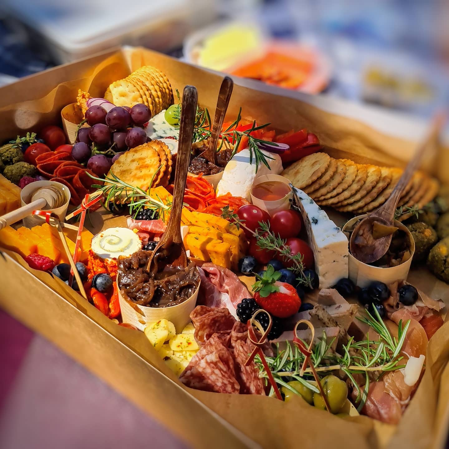 Charcuterie board overflowing with various cheeses, meats, crackers, fruits, and garnishes.