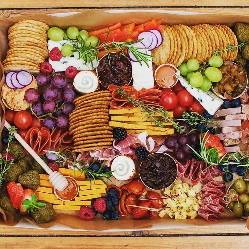 Charcuterie board with crackers, cheese, fruits, meats, and dips.
