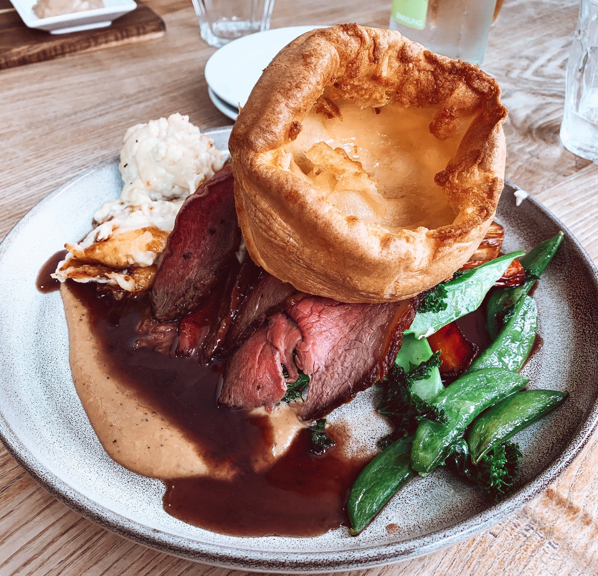 Roast beef dinner with Yorkshire pudding, gravy, vegetables, and mashed potatoes.