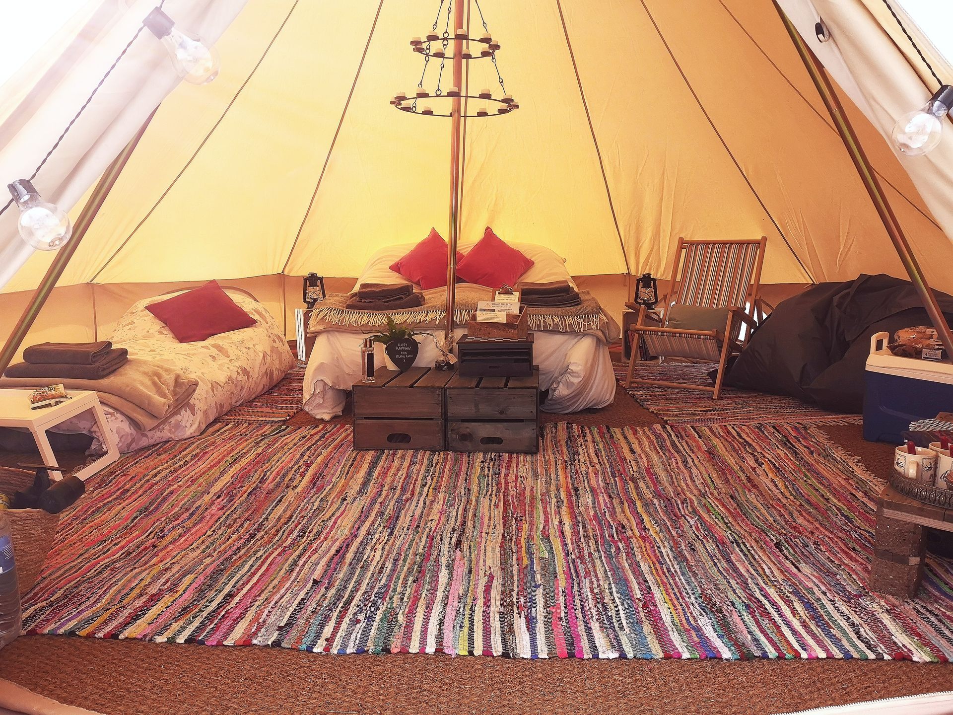 Interior of a glamping tent with bed, rug, and string lights.