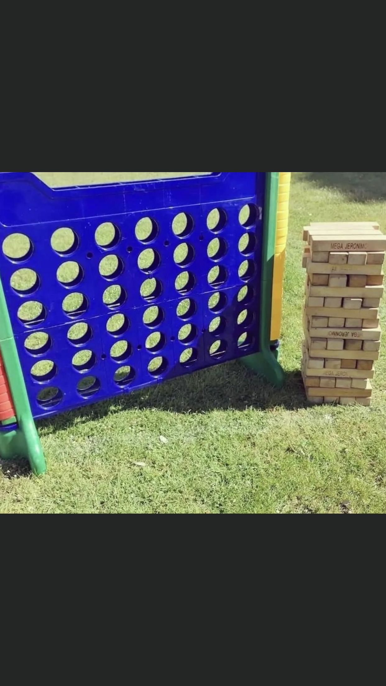 Giant Connect Four game and Jenga blocks on green grass.