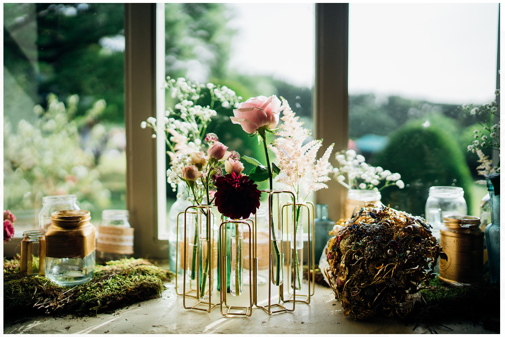 Flowers in glass vases on a windowsill with a garden view; natural light.