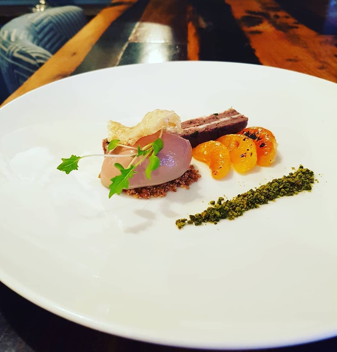 A plate with dessert: a scoop, chocolate block, tangerine segments, a cracker, and green powder.
