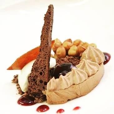 Chocolate dessert with meringue, nuts, and a chocolate shard.