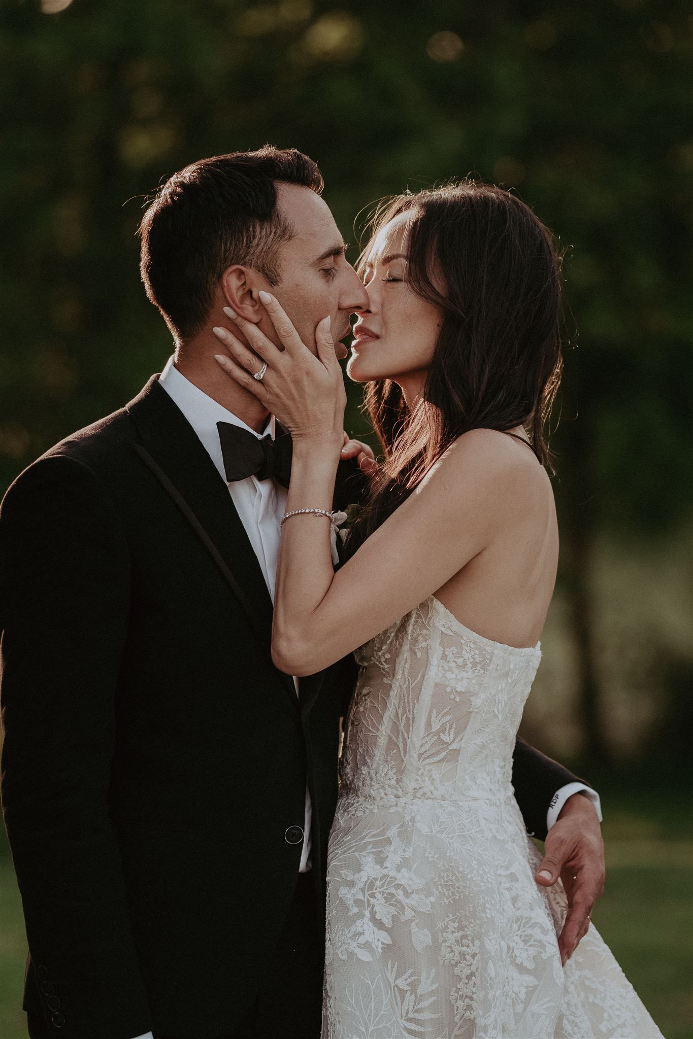 Couple embracing and about to kiss at a wedding. The bride wears a white dress, the groom a black tuxedo.