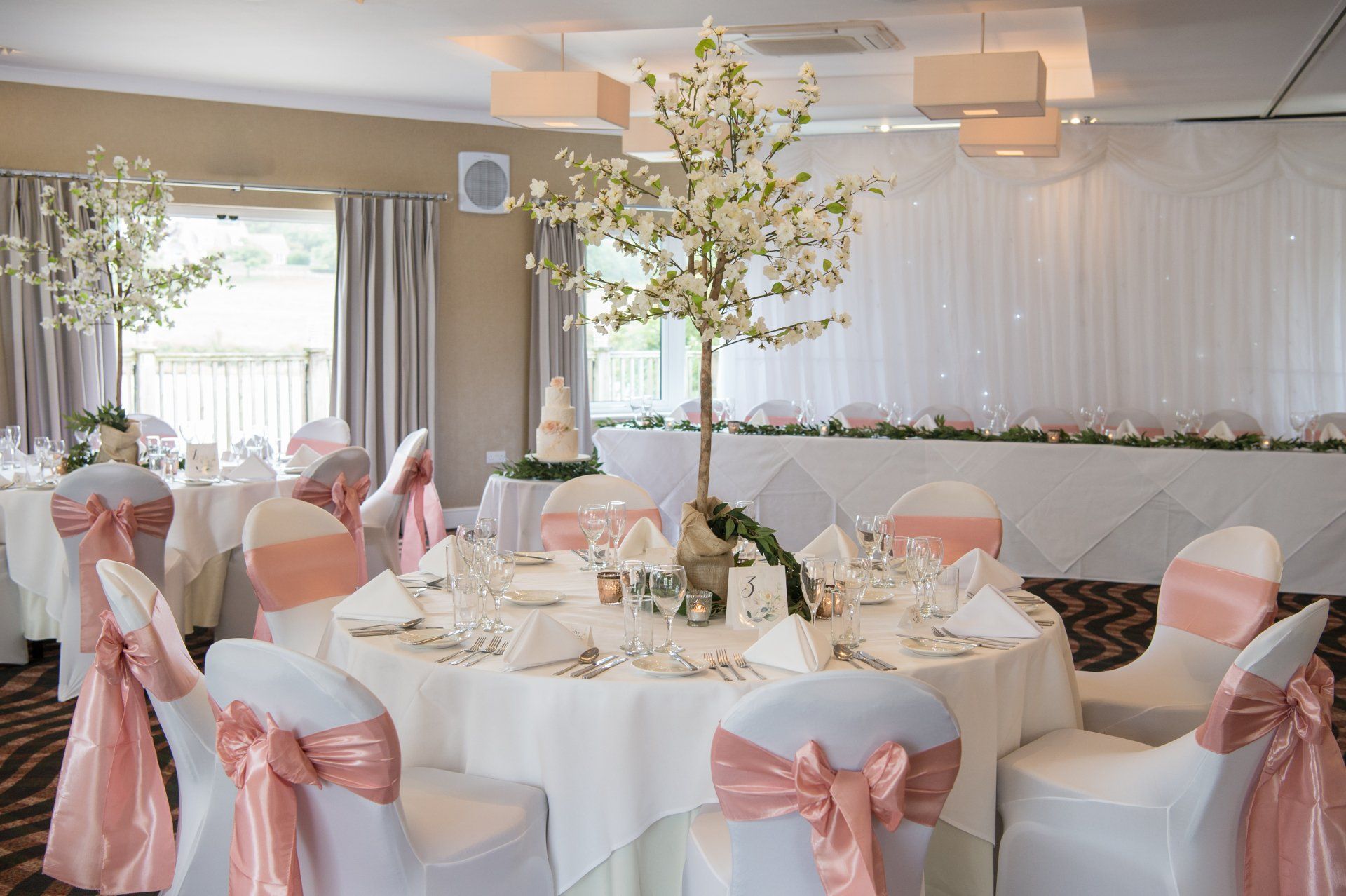 Wedding reception table setting with peach accents and floral centerpieces.