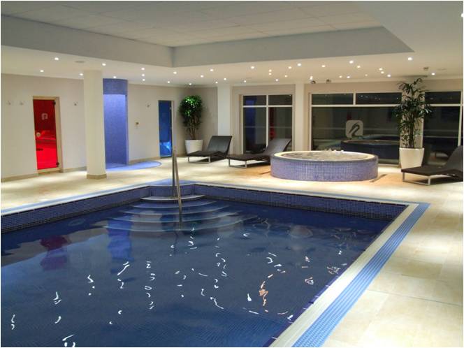 Indoor pool area with pool, jacuzzi, lounge chairs, and blue accents.