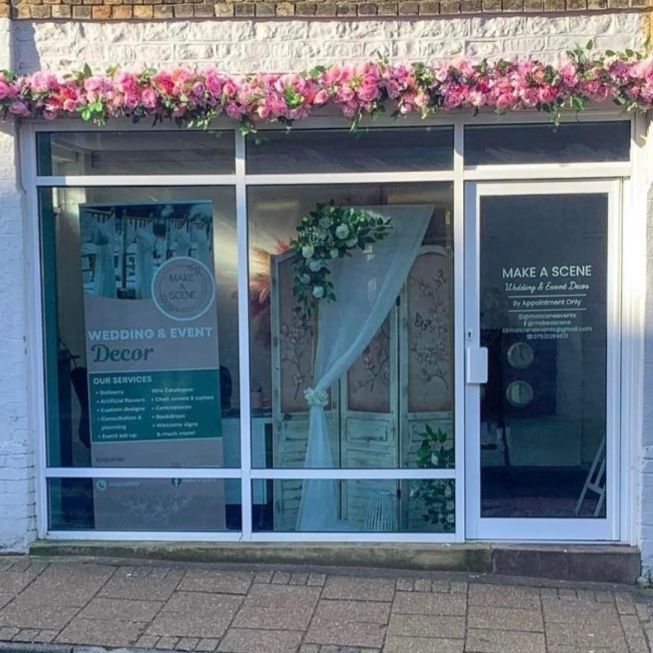Storefront decorated with pink flowers above the window.