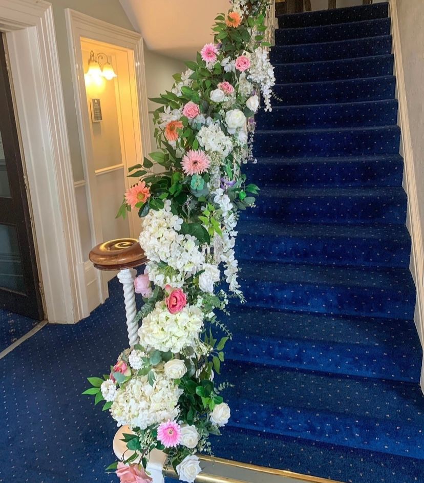 Blue carpeted staircase decorated with flowers and greenery.