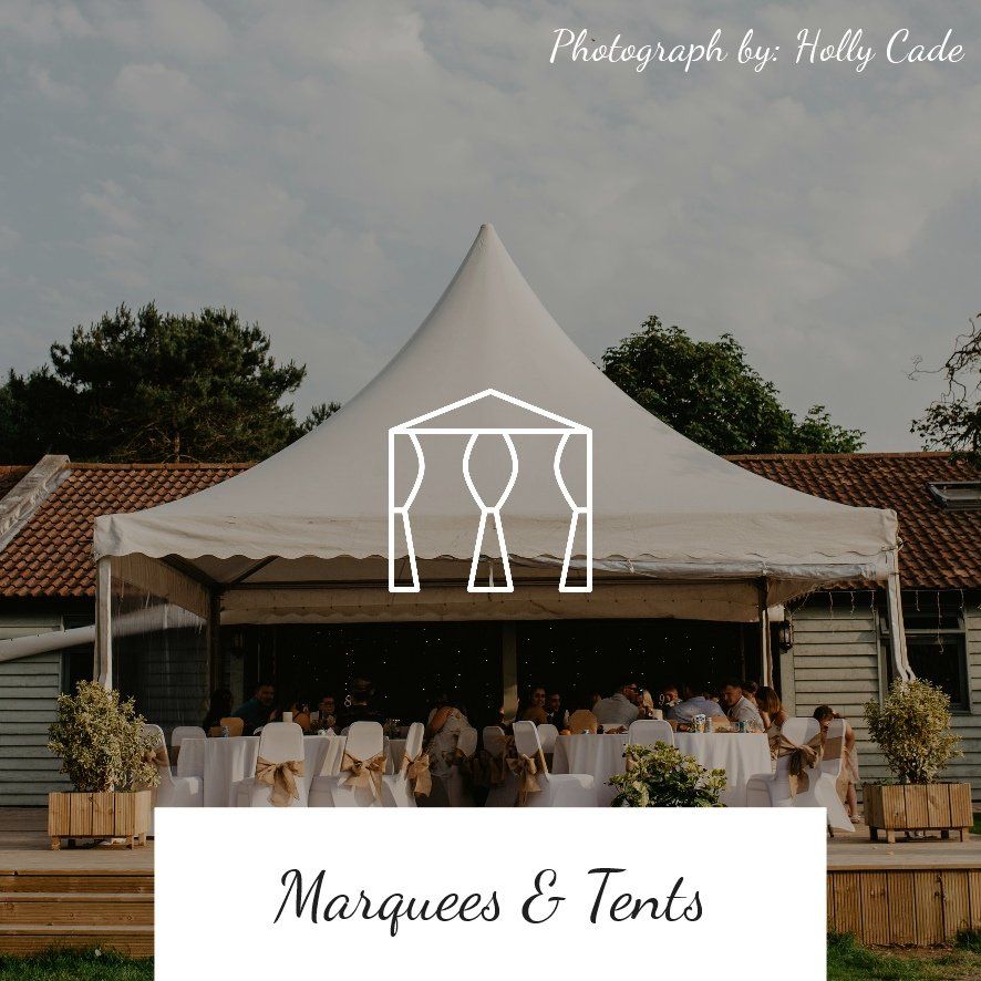 White marquee tent set up for an event, with people seated at tables, wooden building.
