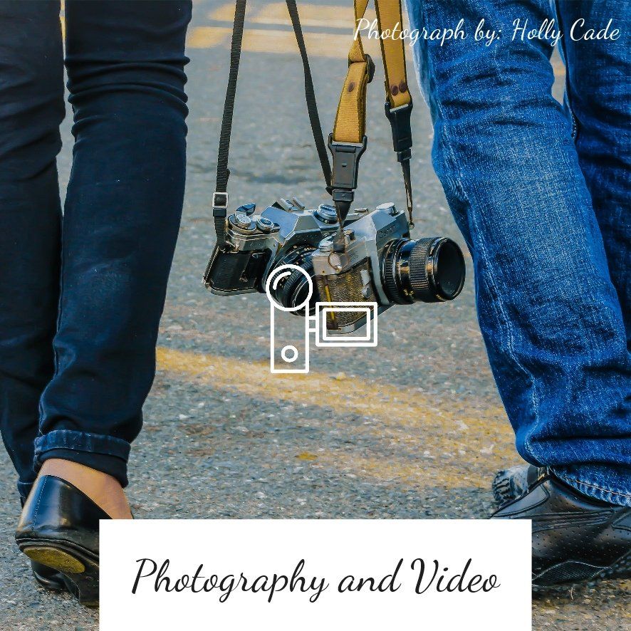 Two people walking, carrying a vintage camera. Blue jeans and black shoes. Photography and video text below.