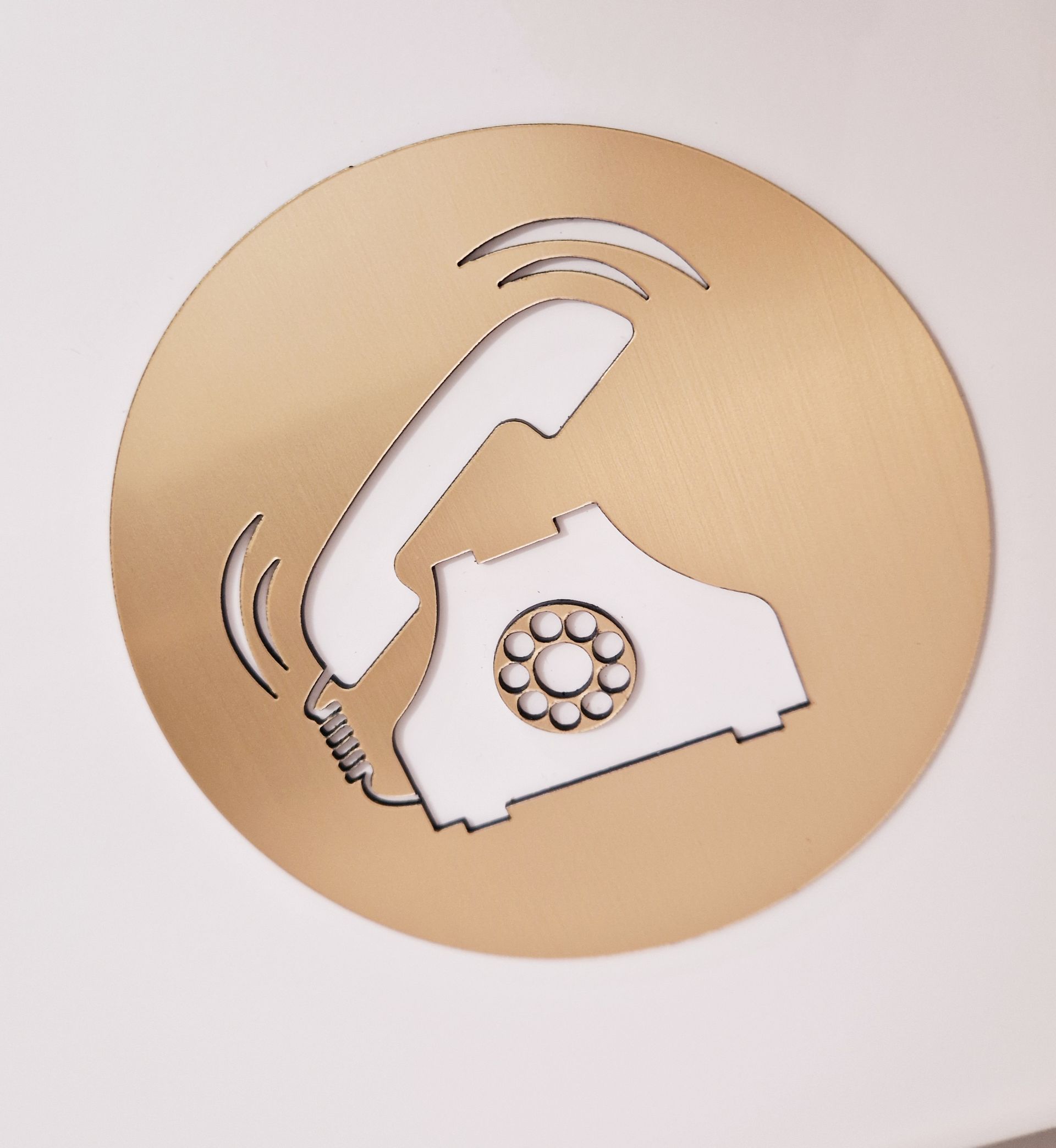 Gold circle with a white cutout of a ringing telephone.