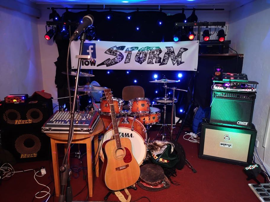 Band stage setup with drums, guitar, amplifier, mixer, and backdrop with