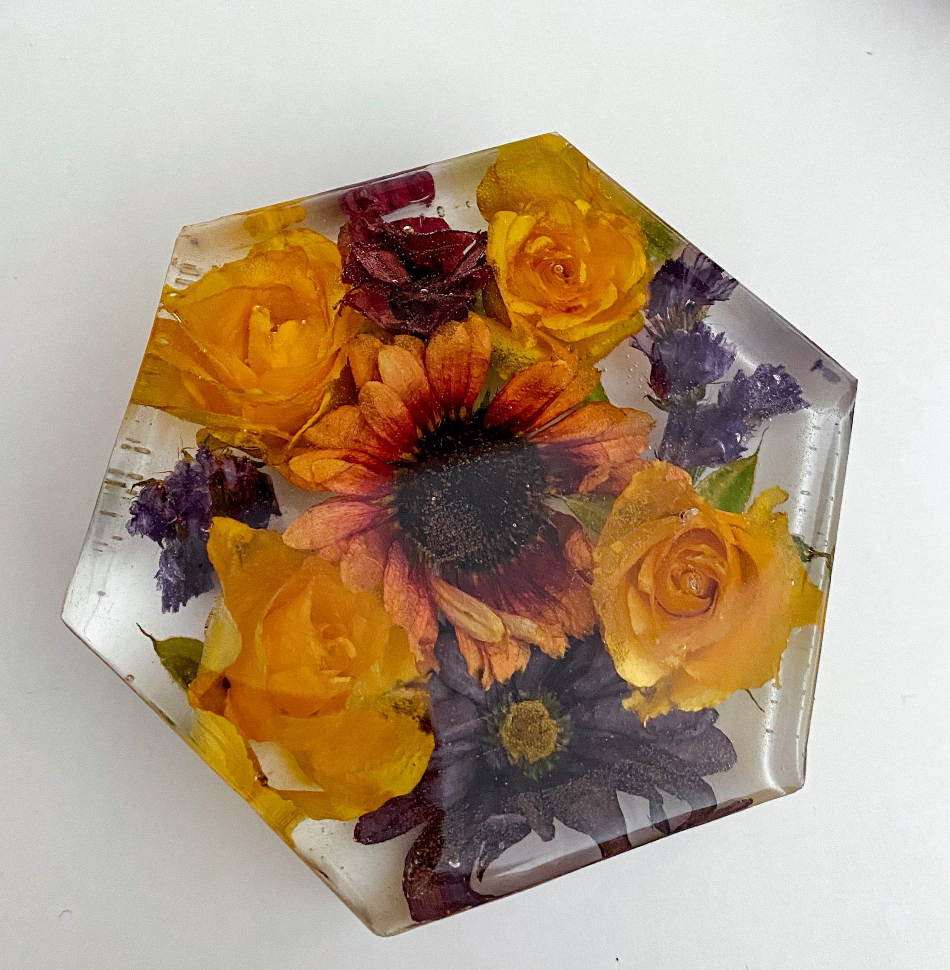 Hexagonal resin coaster with preserved yellow, orange, and purple flowers.