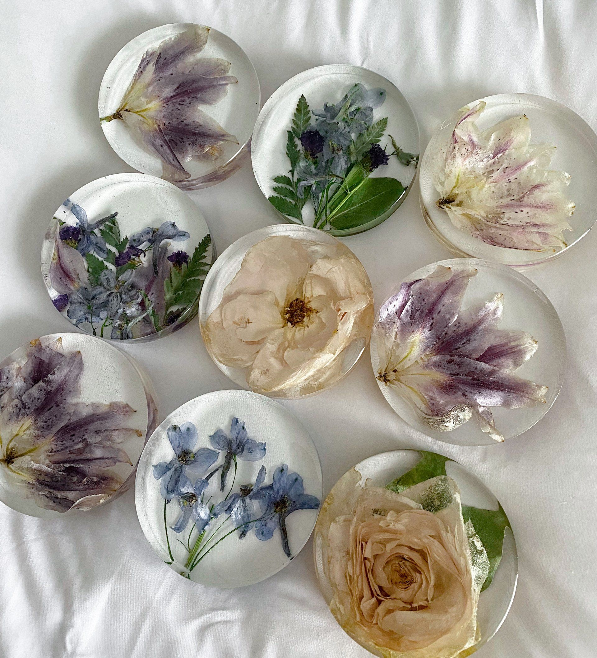 Nine clear resin coasters with pressed flowers.