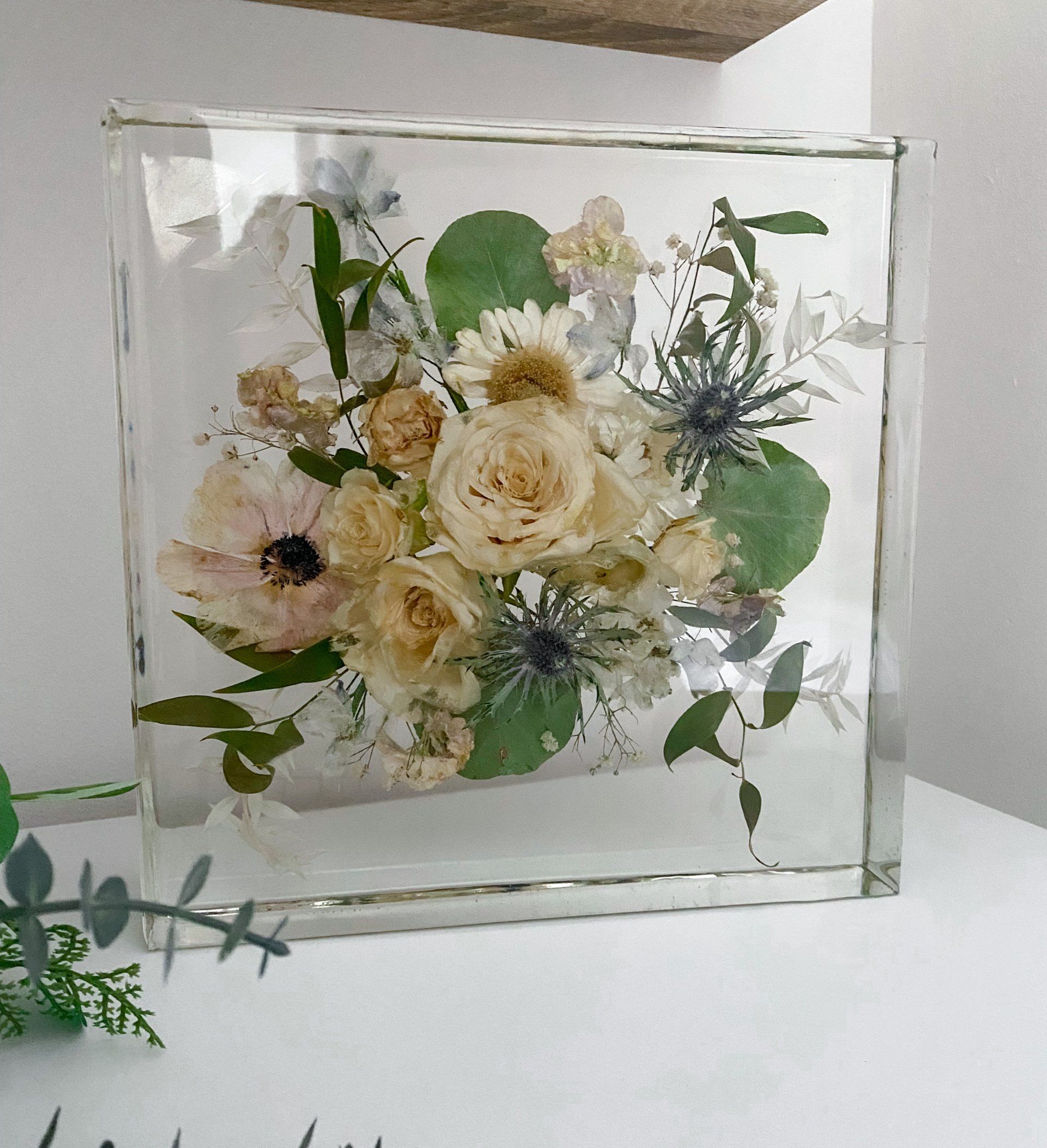 Bouquet of cream and pastel flowers encased in a clear acrylic block.